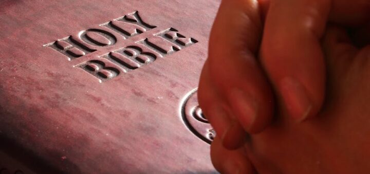 person hands on holy bible