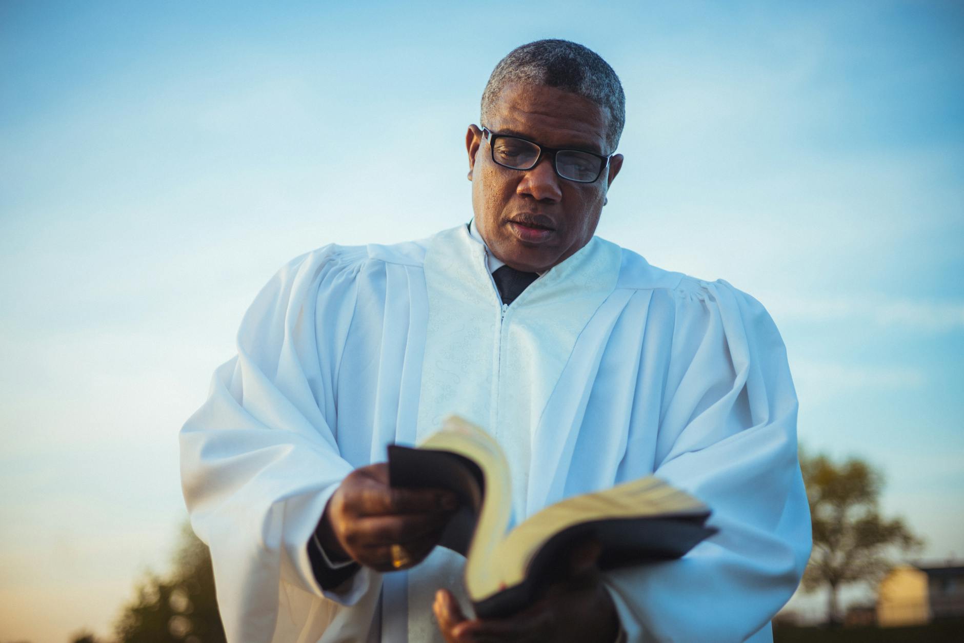priest in glasses looking through a book