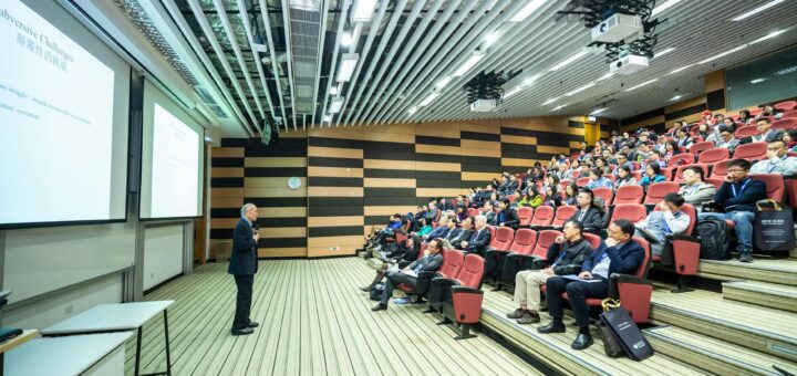 man standing in front of people sitting on red chairs
